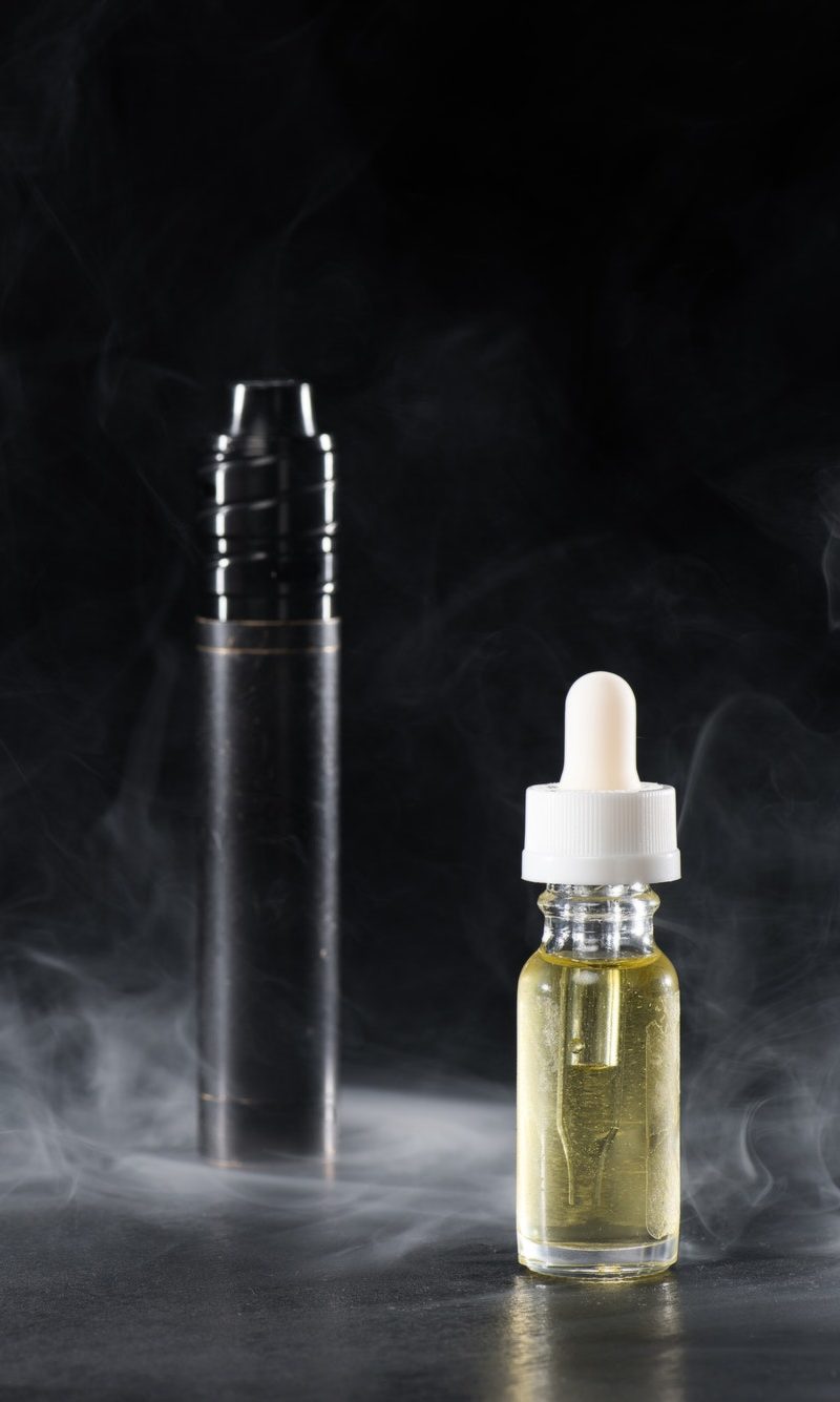 electronic-cigarette-and-liquid-with-clouds-of-smoke-on-dark-background-e1626674164870.jpg