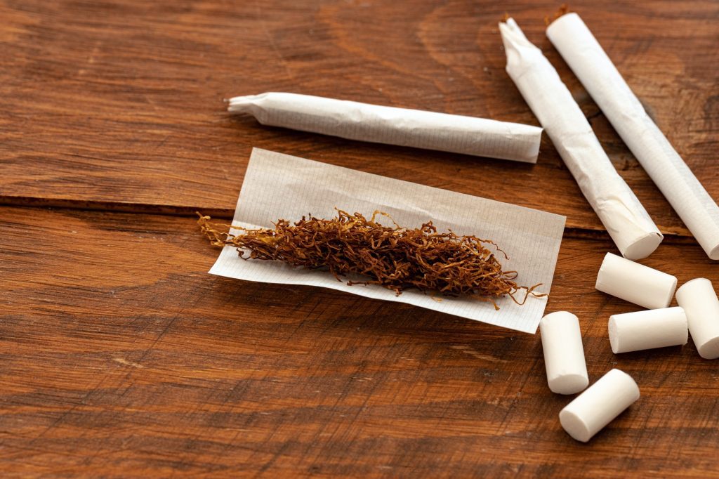 Cigarette paper and pile of tobacco on wooden table